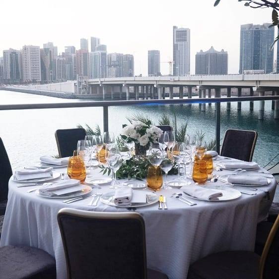 Elegant set table by the water with the Abu Dhabi skyline