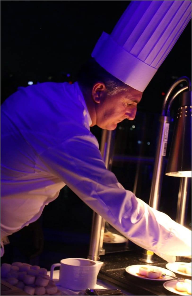 Chef plating desserts under the evening lights