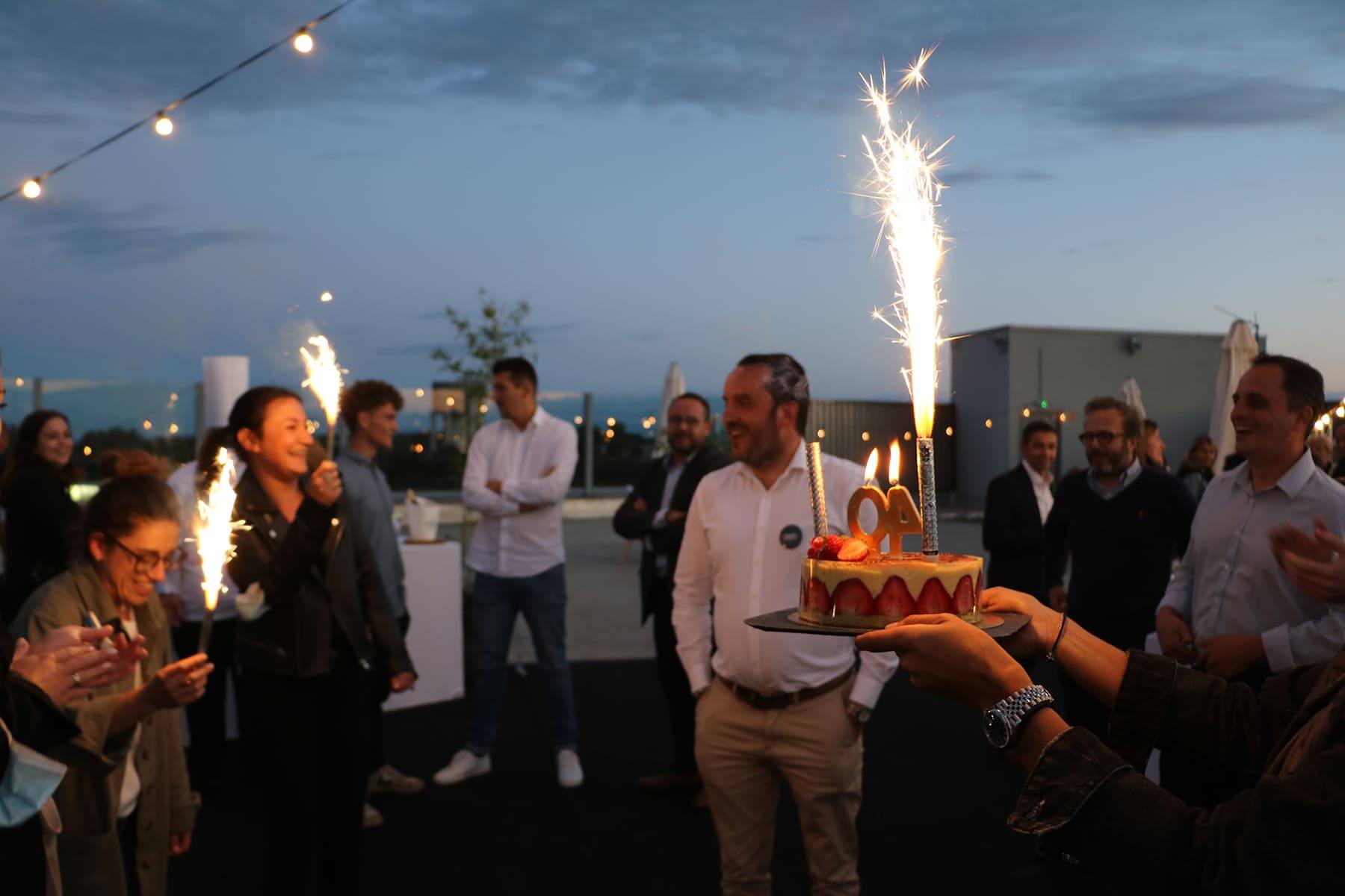 Strawberry cake with sparkler candles carried out as guests cheer at nightfall