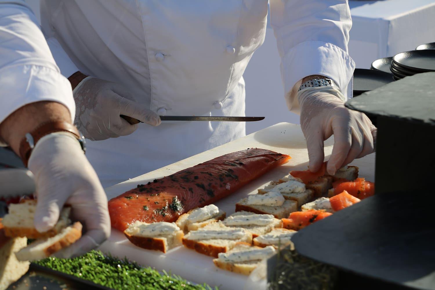 Chef slicing house-cured salmon for canapés at a live station