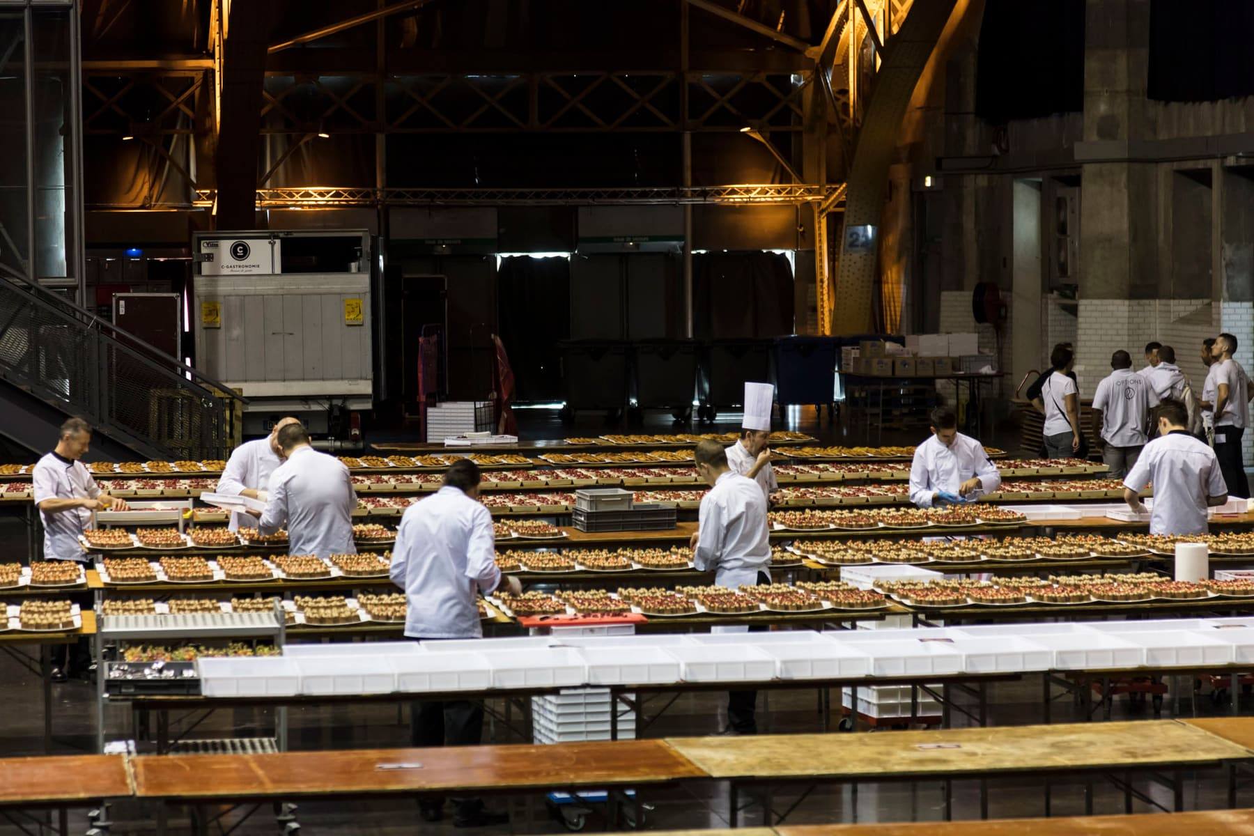 Cooks plating along rows of production tables in the Halles Tony Garnier