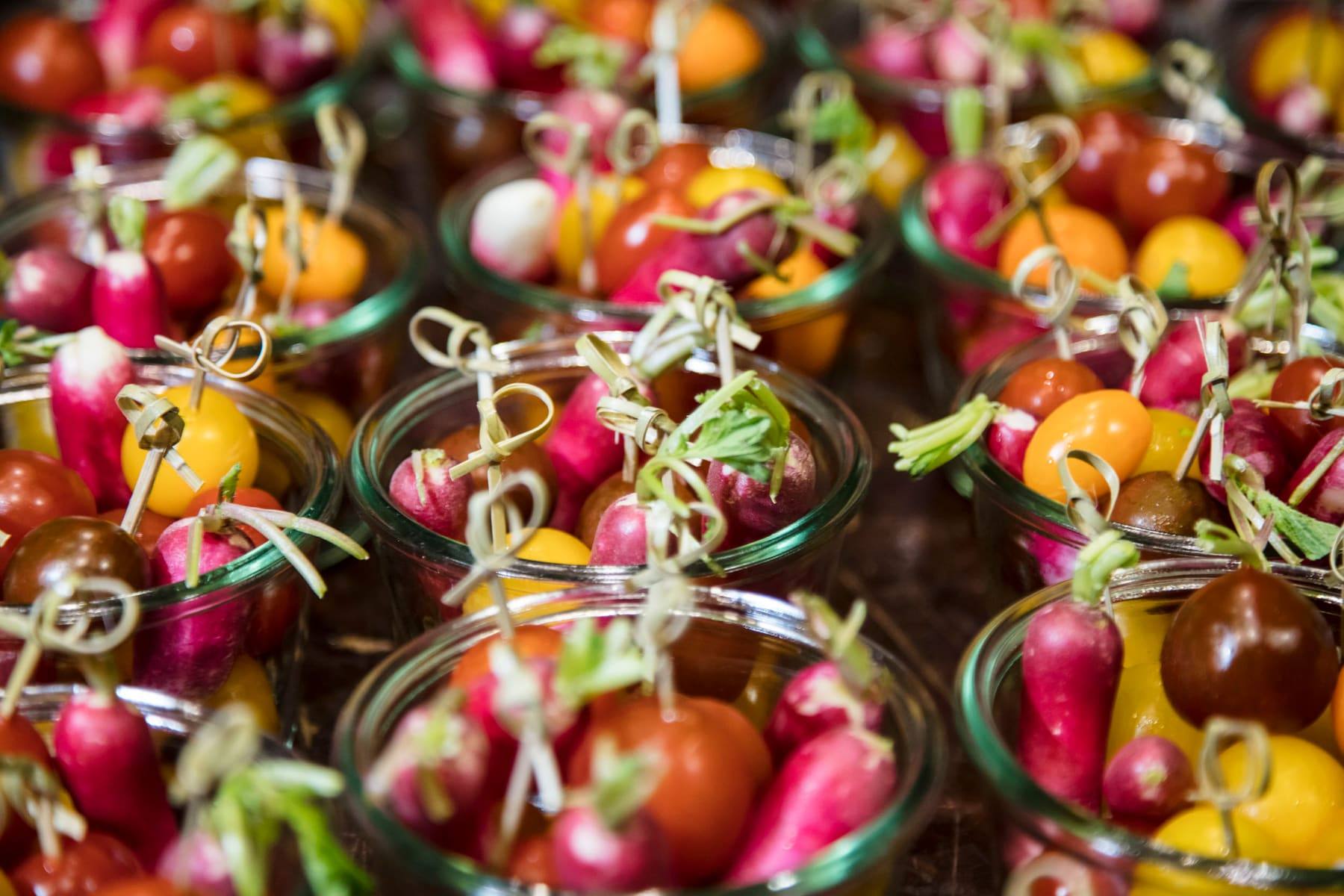 Glass jars of radishes and heirloom tomatoes skewered for an apéritif service