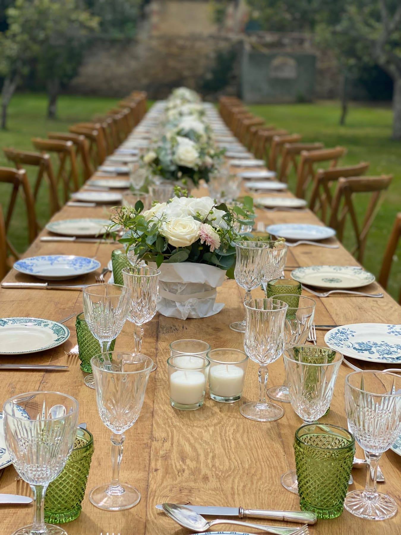 Sommelier in tailored suit setting out crystal glasses and wine beside the château pond