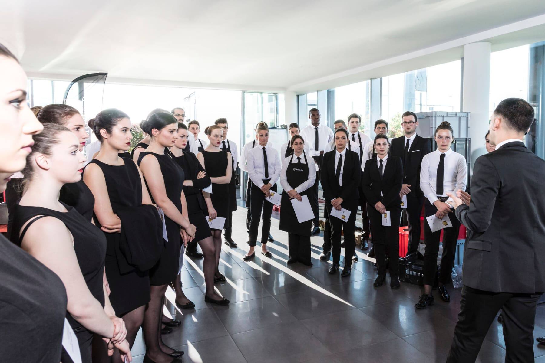 Service team in black briefed before doors open in the daylit showroom