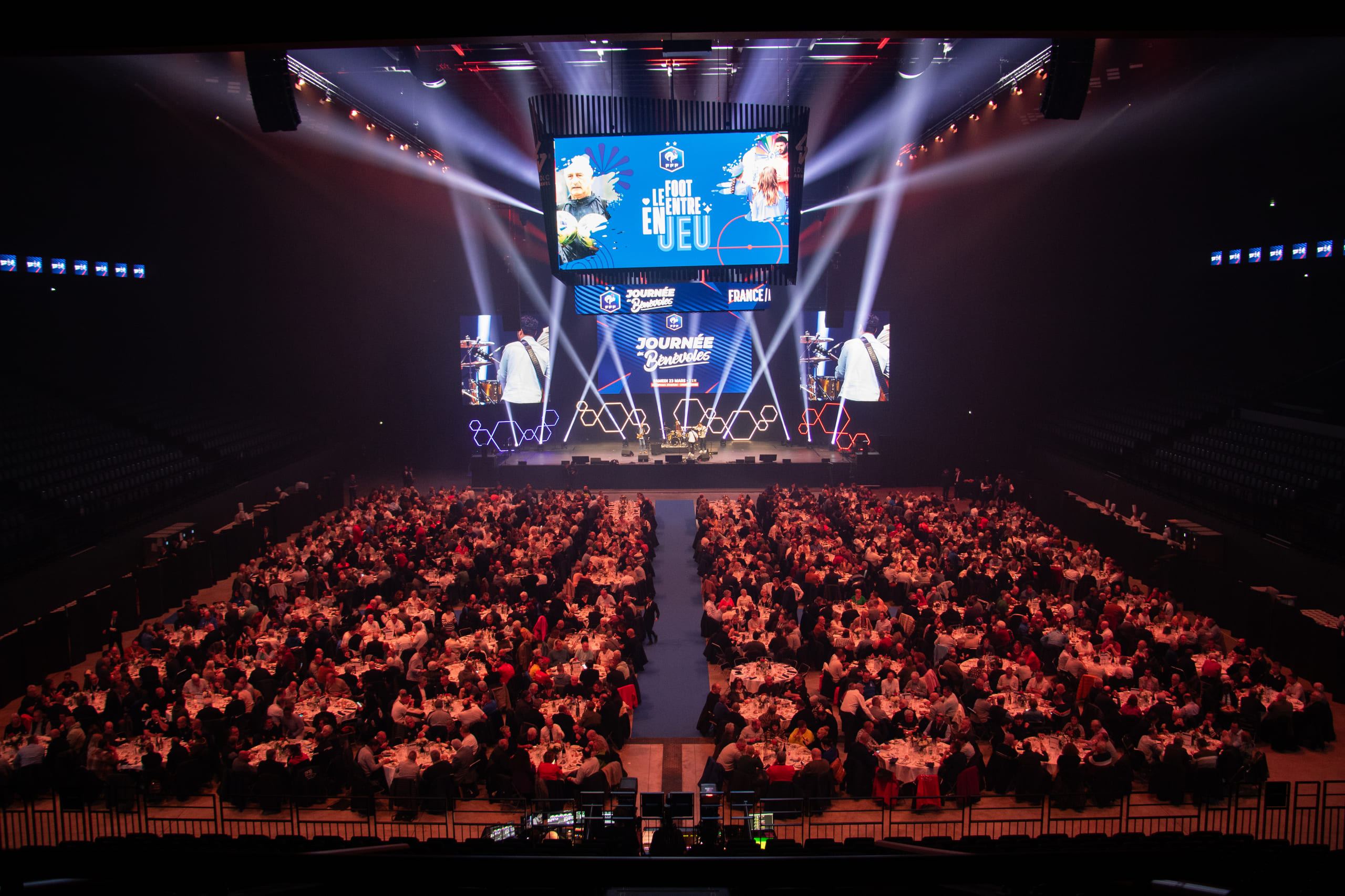 An arena filled with hundreds of banquet tables facing a lit stage
