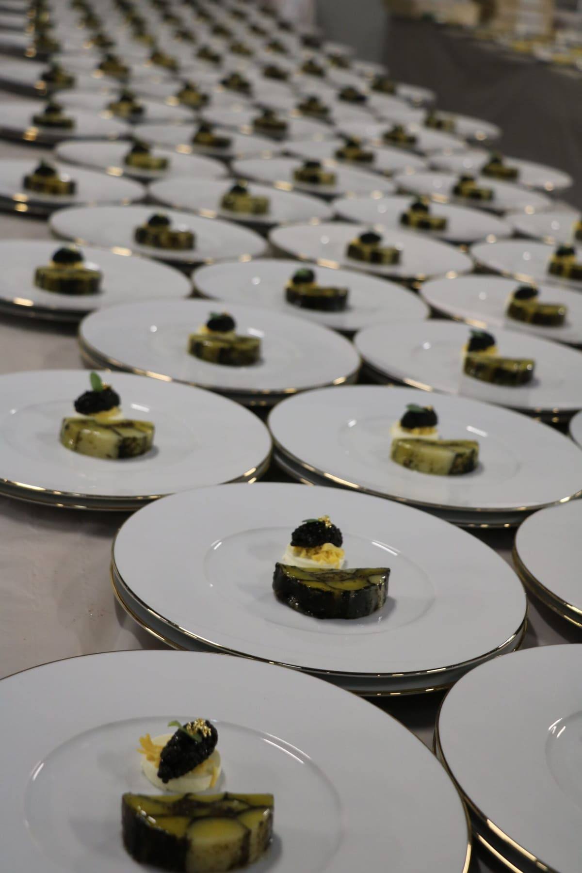 Rows of canapé plates topped with caviar, lined up for service