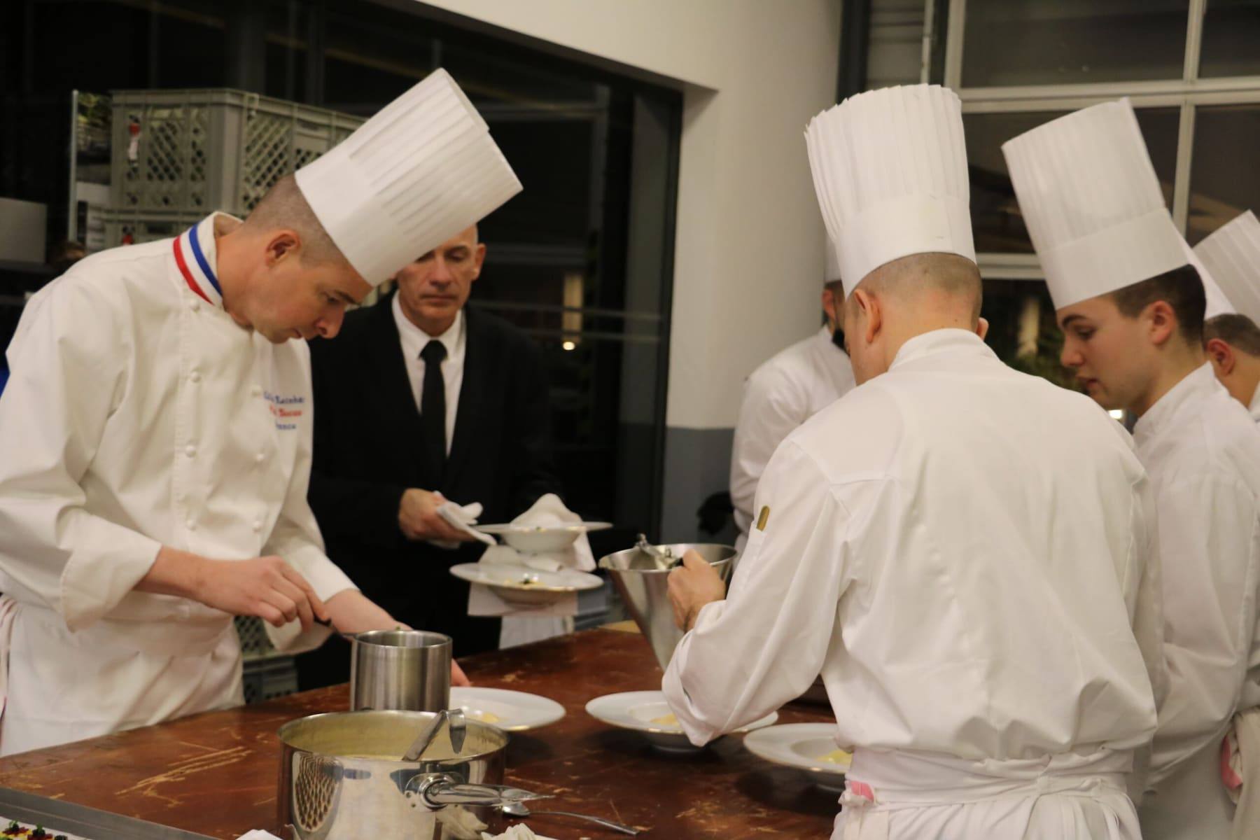 Michelin-starred chef and team plating dishes at a service pass during the dinner