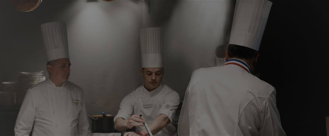 Chefs plating at the Bocuse counter as visitors gather at Taste of Paris